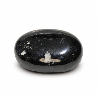 Detailed macro shot of velvety jet-black surface texture resembling tumbled raw Black Tourmaline crystal