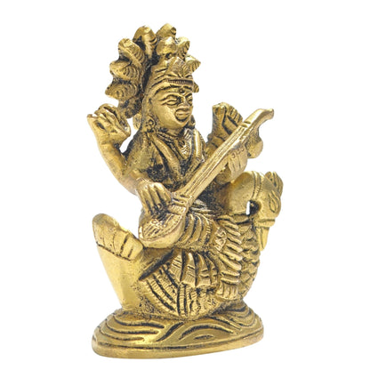 Detailed close-up of intricate brass work showing facial features, ornate mukut crown, veena, rosary beads, and sacred scriptures