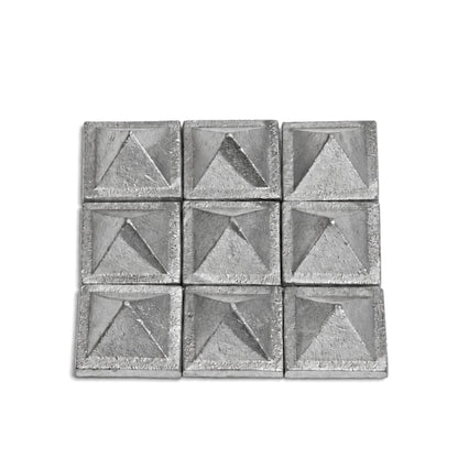 1-inch solid lead pyramid held between fingers demonstrating compact size, dense heavy metal feel, and solid build