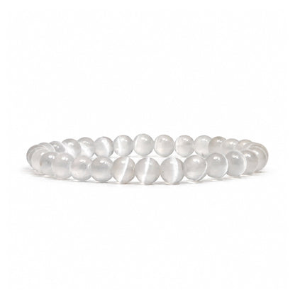 Close-up of 6 mm polished beads highlighting authentic fibrous crystal striations, milky white translucence, and pearlescent chatoyant sheen