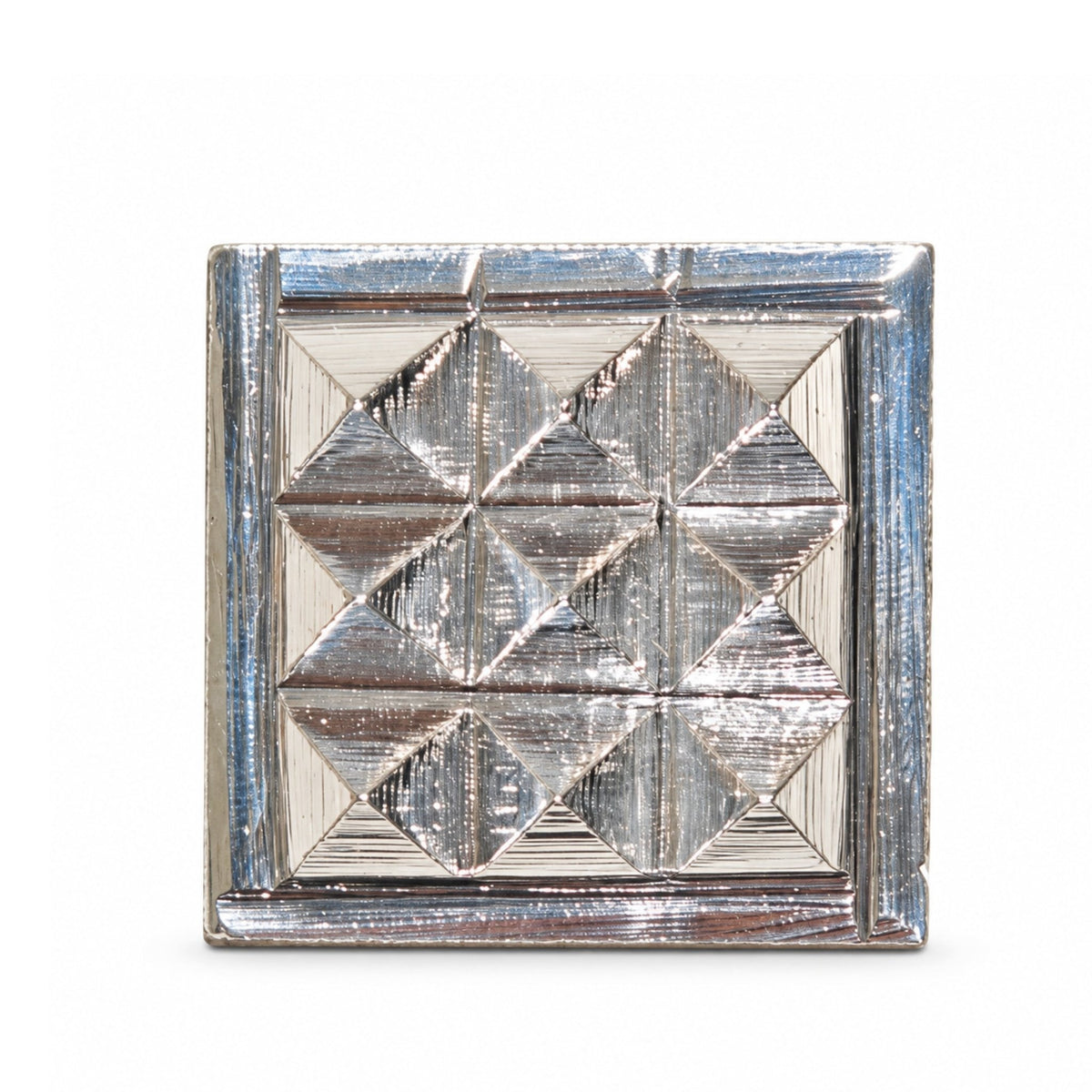 Close-up of silver plated pyramid chip showing high-gloss metallic reflection, precise angular slopes, and sharp apex point