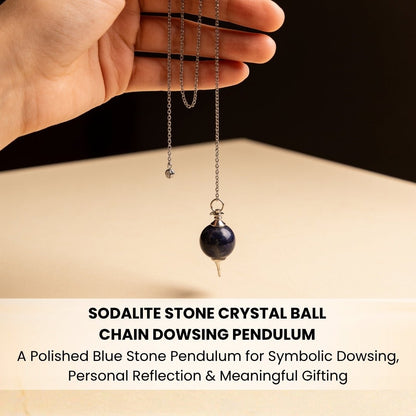 Sodalite crystal ball pendulum held by chain between fingers demonstrating balanced swing and weight