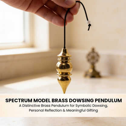 Spectrum brass pendulum suspended from fingers demonstrating ergonomic weight balance and sensitive swing