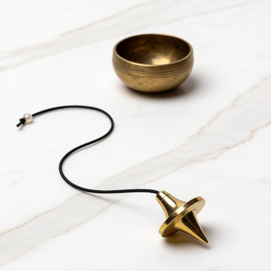 ufo brass dowsing pendulum with chain on a plain background