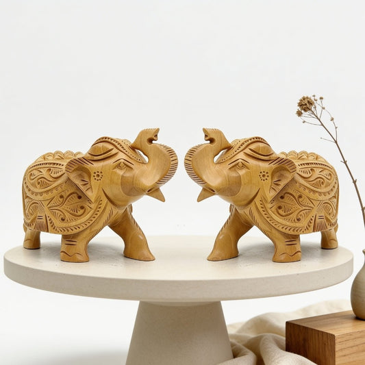 pair of light brown carved wooden elephant statues with raised trunks