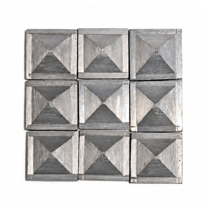 Set of 1-inch solid zinc pyramids resting in open hand demonstrating compact size, substantial metallic weight, and smooth finish